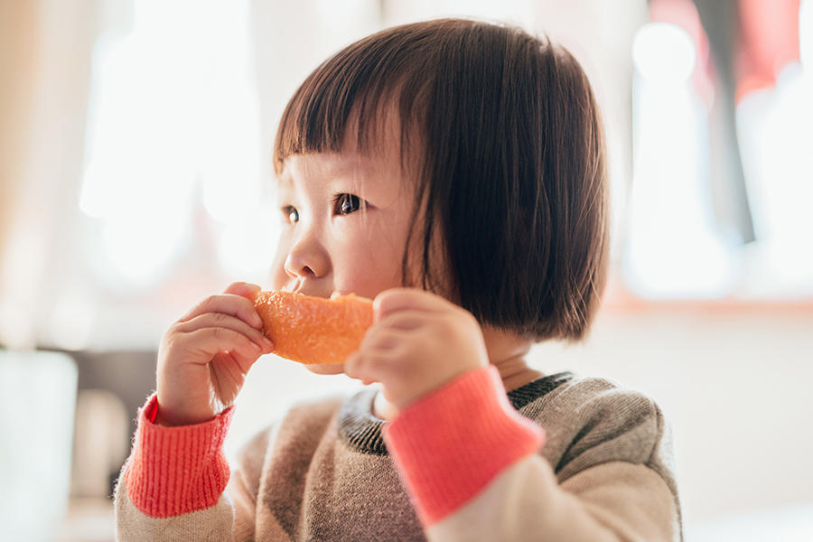 baby girl eating orange